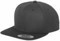 A plain black snapback hat with a flat brim, featuring a small, round sticker on the brim indicating it is a YP001 by Flexfit By Yupoong and providing information about its style and brand.