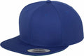 A Flexfit By Yupoong YP001 snapback cap with a flat brim in blue, featuring a silver sticker with text on the brim and visible stitching on the panels.
