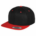 A Flexfit By Yupoong YP002 baseball cap, showcasing a black crown with a red brim, complemented by red eyelets and a top button. The brim features a Snapback sticker.