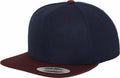 A YP002 snapback cap from Flexfit By Yupoong, featuring a navy blue color with a maroon brim and a sticker on the front.