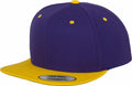 A YP002 snapback cap by Flexfit By Yupoong, featuring a purple crown adorned with yellow eyelets and a vibrant yellow brim. A sticker on the brim confirms its snapback style.