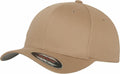 The YP004 baseball cap by Flexfit By Yupoong is tan with a curved brim and adorned with a circular sticker. It features six panels with eyelets and has a clean, logo-free design.