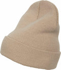 The YP012 beanie from Flexfit By Yupoong, featuring a beige knitted design and a folded brim, is displayed against a plain white background. The beanie is slightly tilted to highlight its texture and soft fabric.