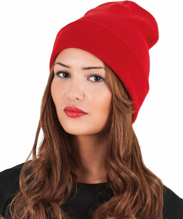 A person with long, wavy brown hair is wearing a red YP012 by Flexfit By Yupoong and a black top. The background is plain white.
