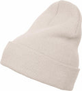 The Flexfit By Yupoong YP012 is a soft beige knit beanie featuring a folded cuff, showcased at an angle to highlight its simple design and texture.