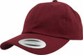 A maroon baseball cap with a curved brim and a round white label on the front depicting the brand Flexfit By Yupoong and text YP022.