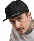 Close-up of a man wearing a black Flexfit By Yupoong YP037 cap, white sweatshirt, and displaying visible tattoos on his neck and face.
