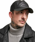 A person wearing a black leather cap (Flexfit By Yupoong YP038), black leather jacket, and gray turtleneck sweater, looking to the side with a neutral expression.