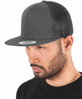 A man wearing a dark Flexfit By Yupoong YP040 and a black T-shirt is shown in this close-up image.