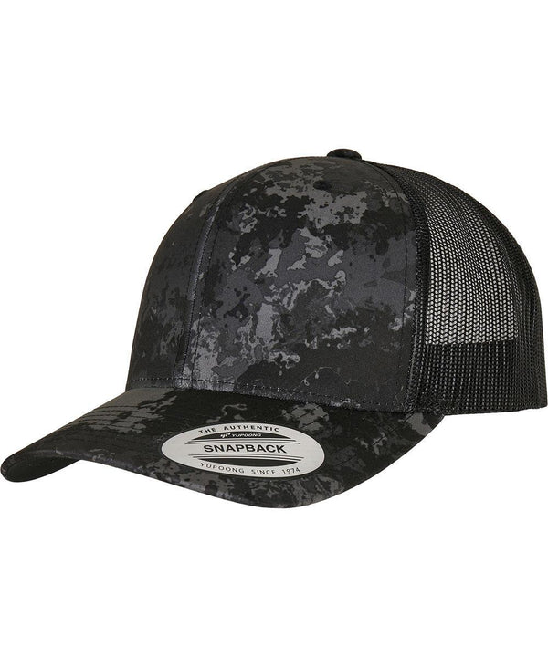 The Flexfit by Yupoong YP Classics Veil Camo retro trucker cap (6606VC) features a black and grey camo pattern, curved brim, black mesh back panels, and a round manufacturer sticker on the brim.