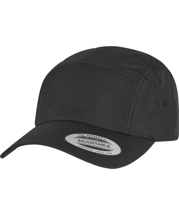 The Flexfit by Yupoong Jockey Elastic Cap (9300) is a black adjustable baseball cap featuring a curved peak and a front-peak sticker that reads “The Authentic Adjustable Yupoong Since 1974.”.