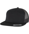 The Flexfit by Yupoong 7-panel classic trucker cap (9294) features a black flat peak, solid black front, mesh back panels, an adjustable snapback fastening, and a sticker on the peak.