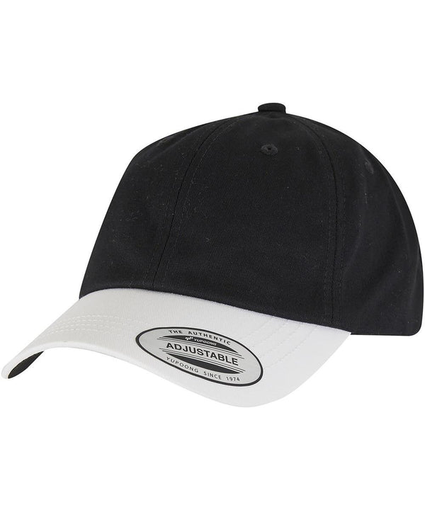 The Flexfit by Yupoong Low-profile cotton twill two-toned (6245CMT) cap features a black crown, white curved brim with a labelled tag, adjustable strap, and top button. Photographed on a white background.